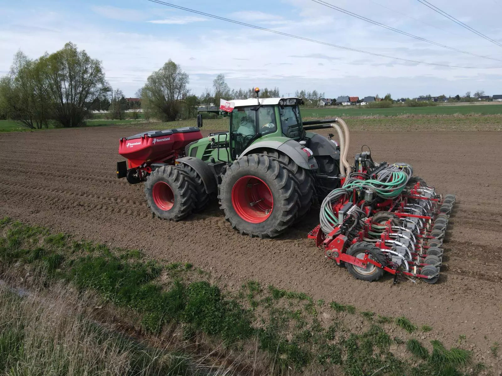A Fendt tractor with a precision drill and a front fertiliser hopper during spring sowing